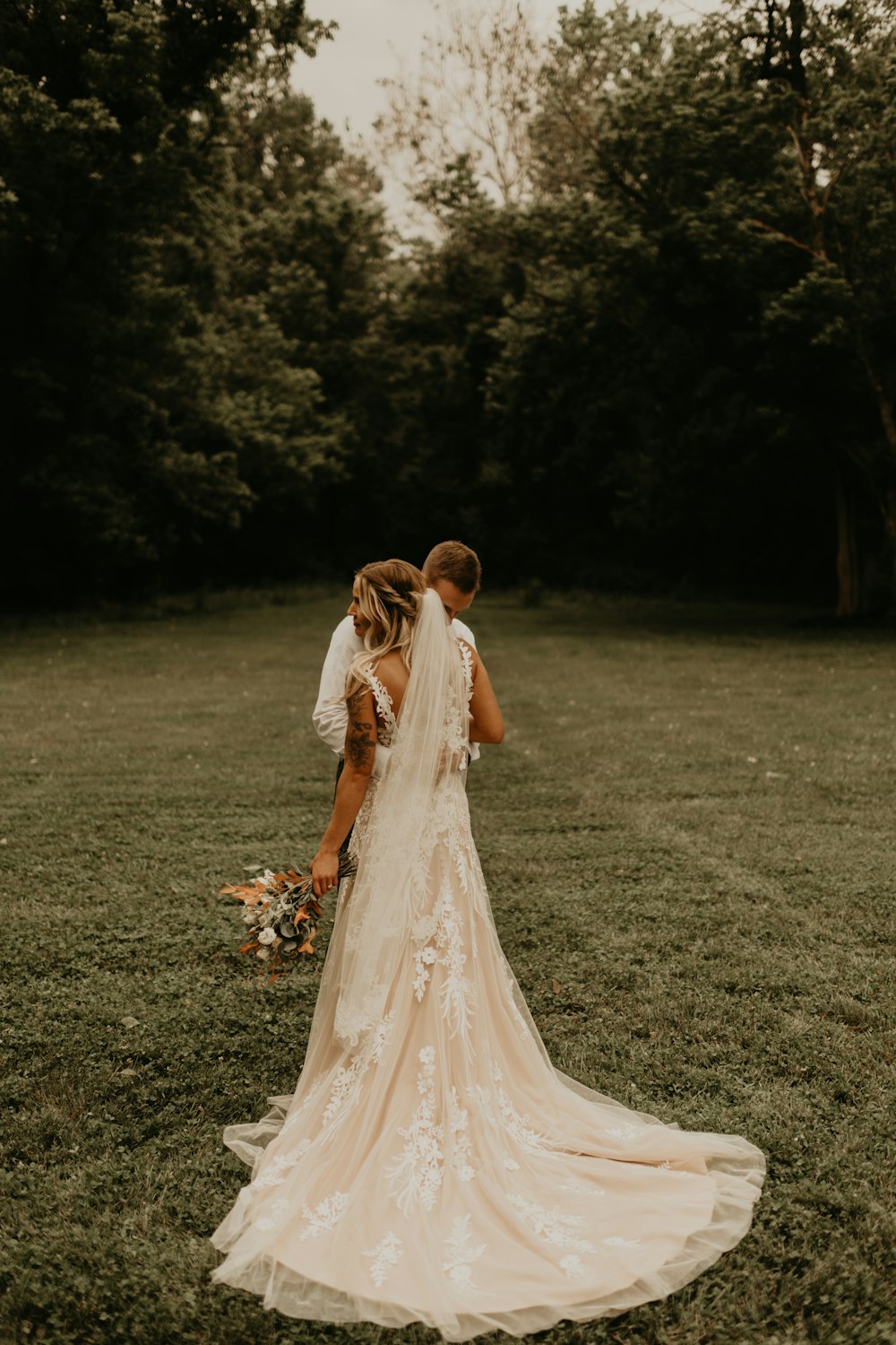 woman in white wedding dress standing on green grass field during daytime