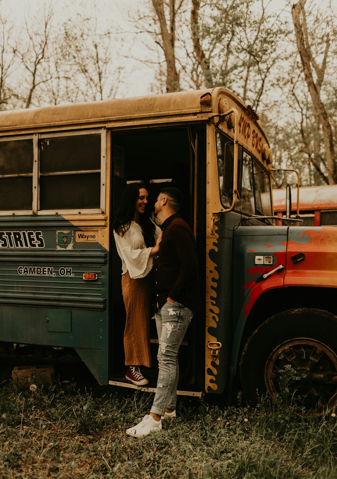 woman in white long sleeve shirt and blue denim jeans standing on yellow school bus during