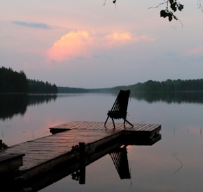 brown wooden bench on dock near lake during daytime