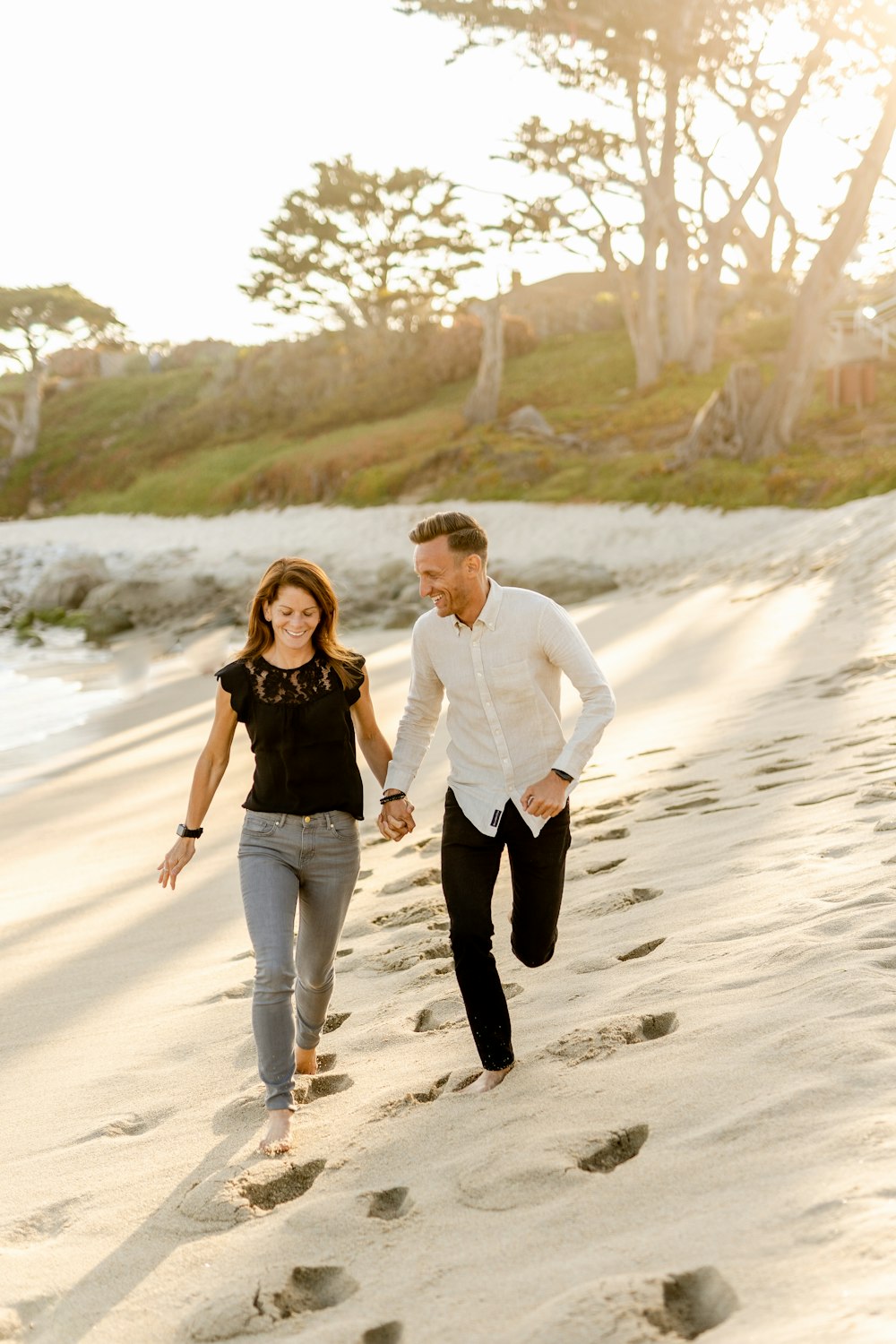 하얀 드레스 셔츠를 입은 남자와 낮 동안 해변을 걷고 있는 검은 드레스를 입은 여자