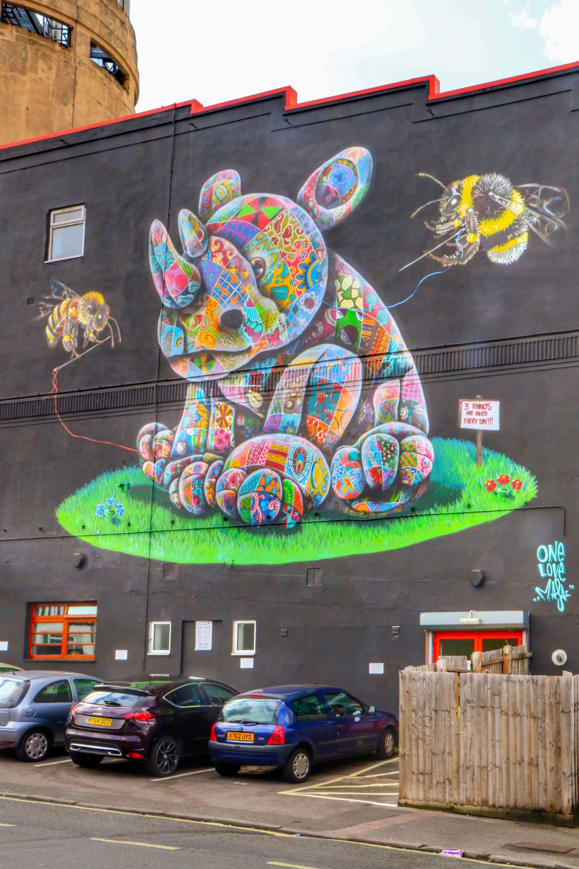 A mural of a patchwork rhinoceros, being sewed by two bees.