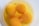 Four raw egg yolks floating in egg white inside a white bowl. Small bubbles are present on the surface of the egg whites.