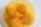Four raw egg yolks floating in egg white inside a white bowl. Small bubbles are present on the surface of the egg whites.