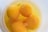 Four raw egg yolks floating in egg white inside a white bowl. Small bubbles are present on the surface of the egg whites.
