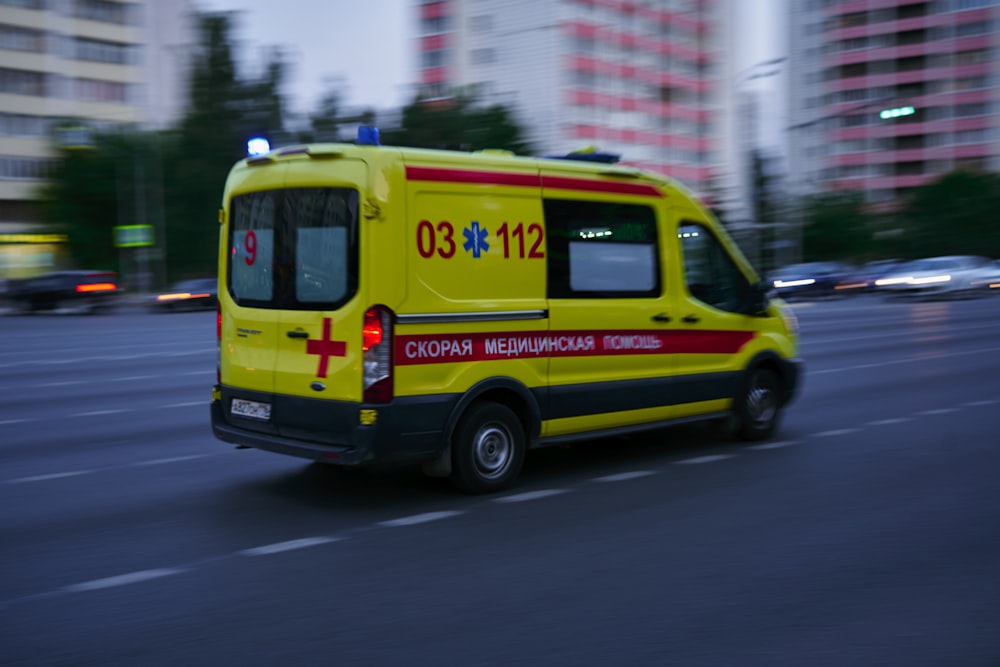 yellow and red ambulance on road during daytime