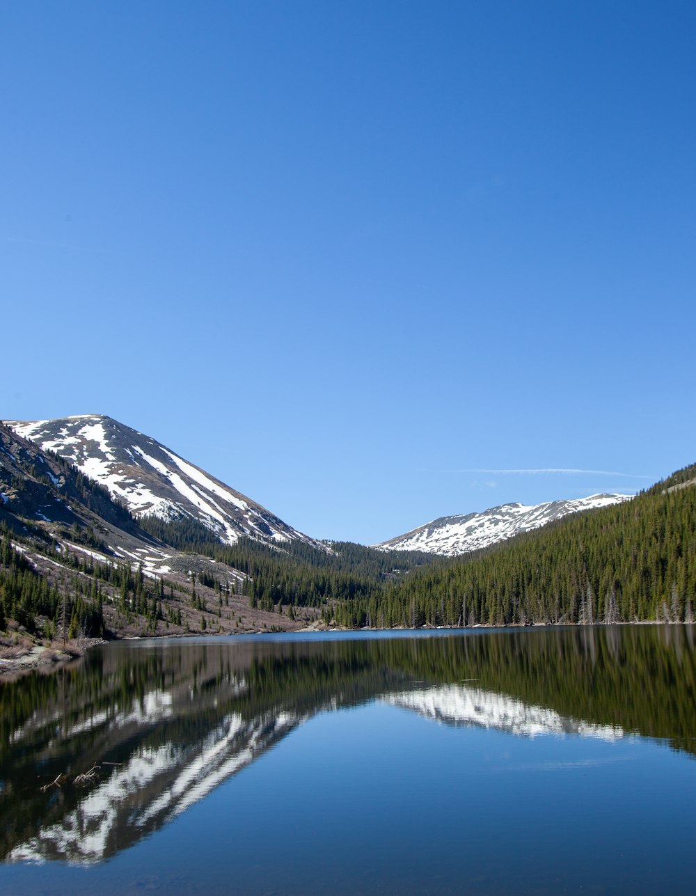 lake near snow covered mountain under blue sky during daytime