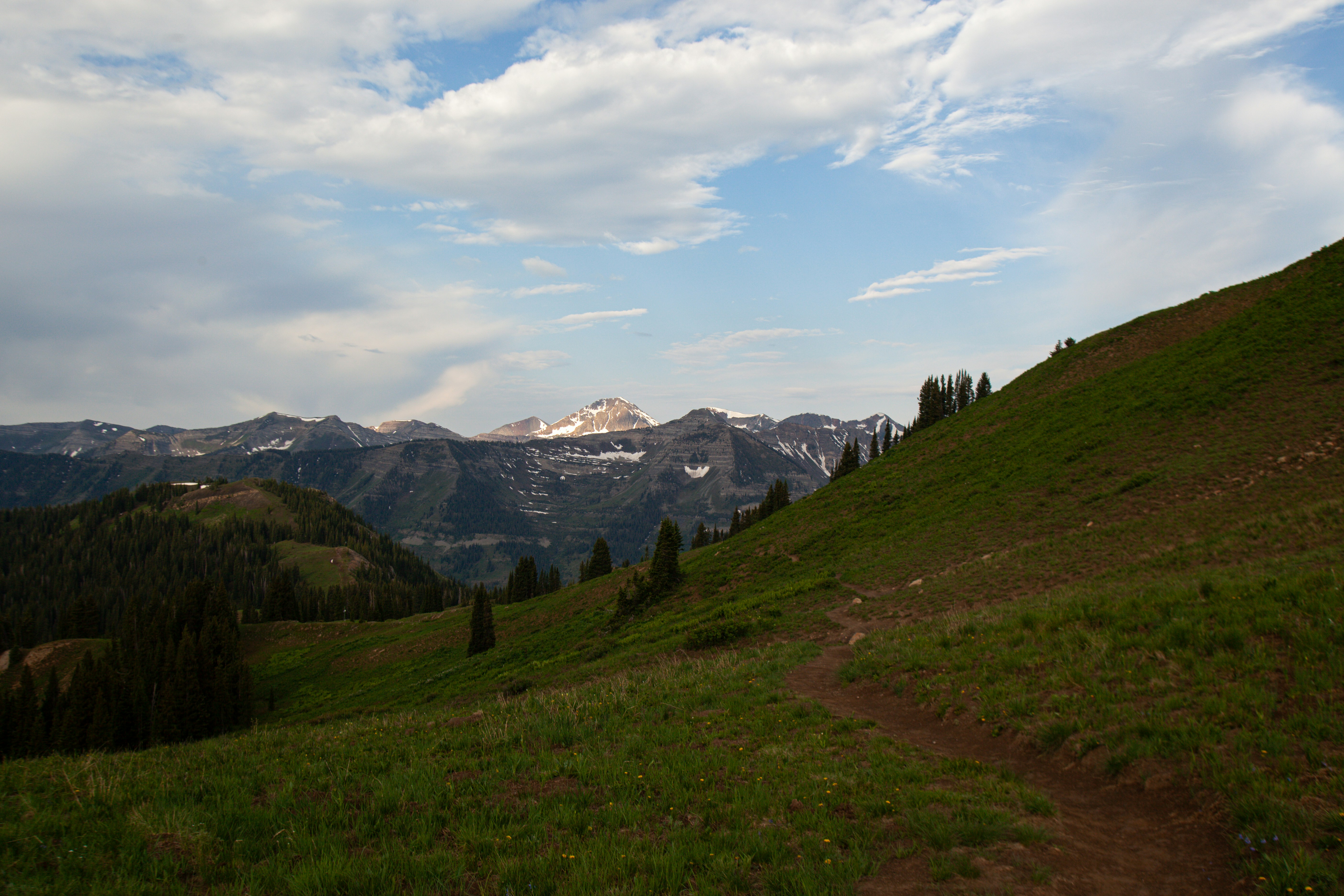 A hiker on a mountain trail with layered vista behind them.