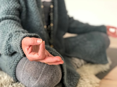 Close-up of hands resting on knees in a mudra pose during meditation.