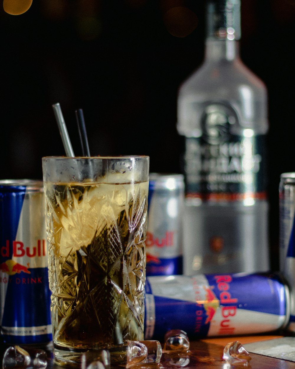 clear drinking glass with ice cubes and straw