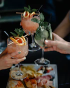 person holding clear wine glass with orange juice