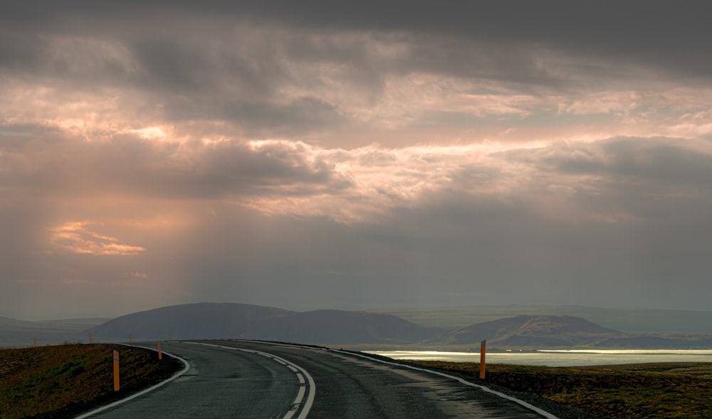 Schwarzes Auto auf der Straße unter grauen Wolken