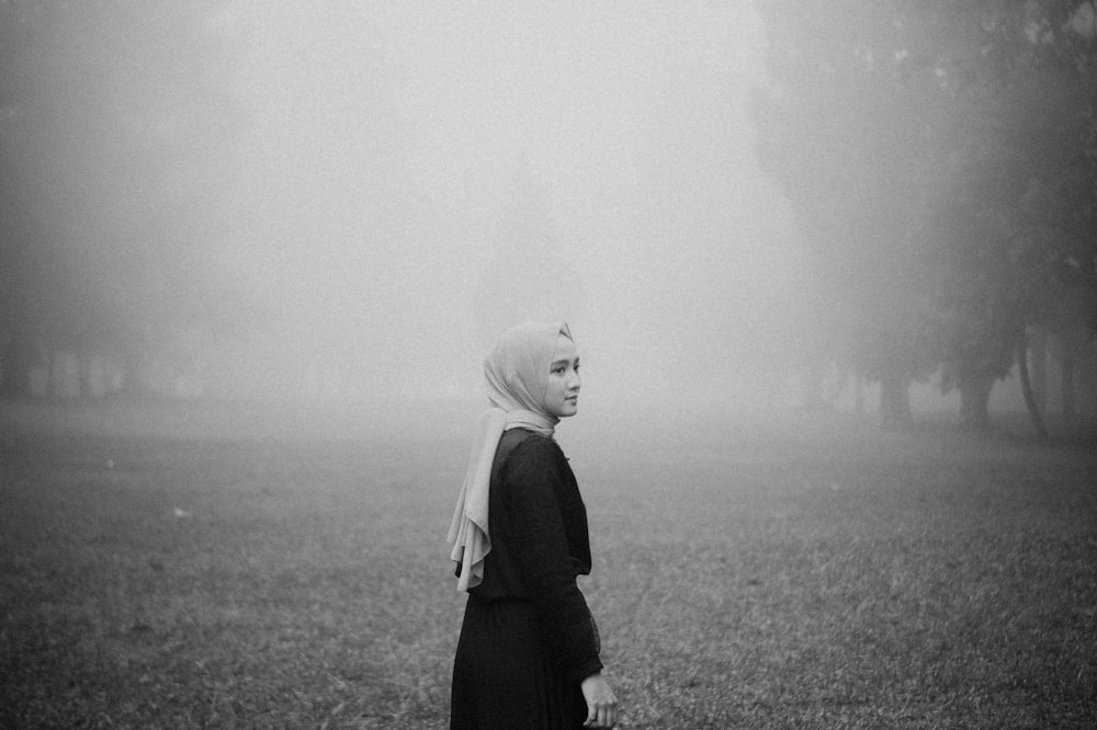 woman in black coat standing on grass field