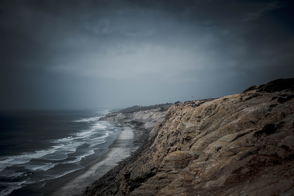 brown rocky shore near body of water during daytime