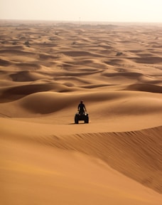 person in black jacket sitting on sand during daytime
