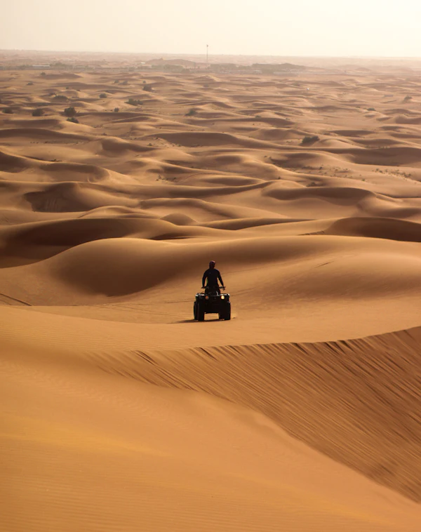 Person sitting on a sand dune in daylight