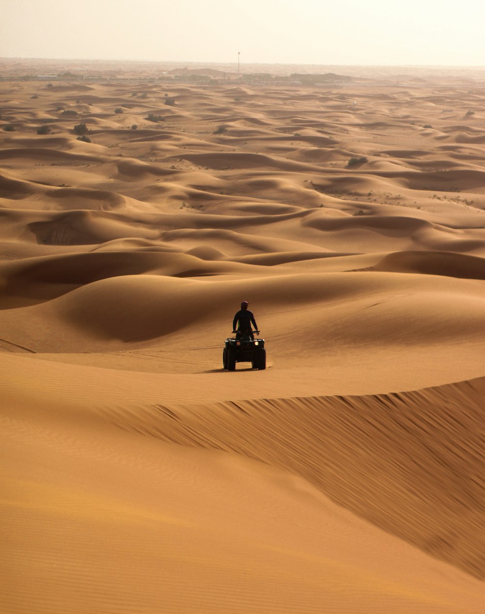 Persona con chaqueta negra sentada en la arena durante el día