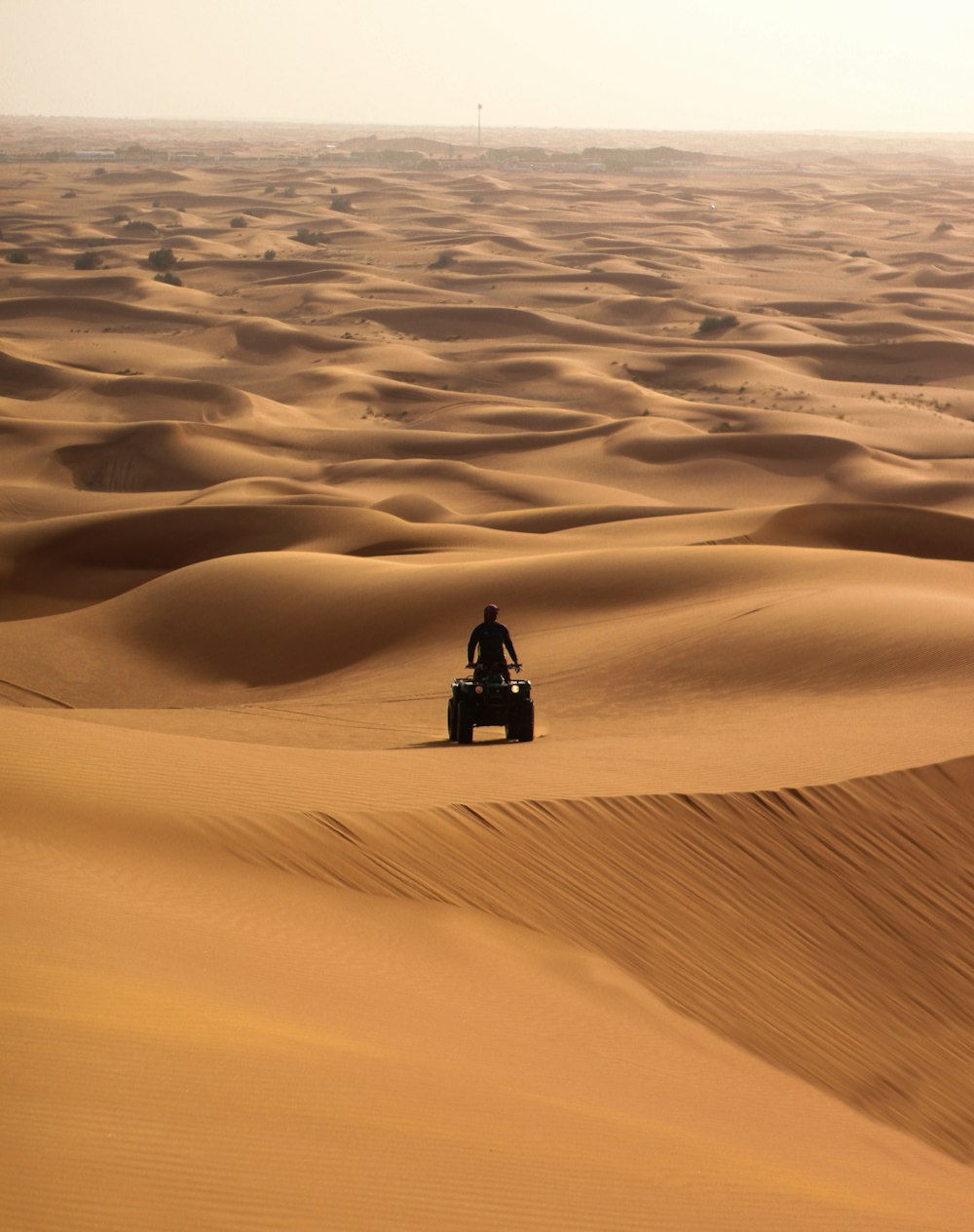 person in black jacket sitting on sand during daytime