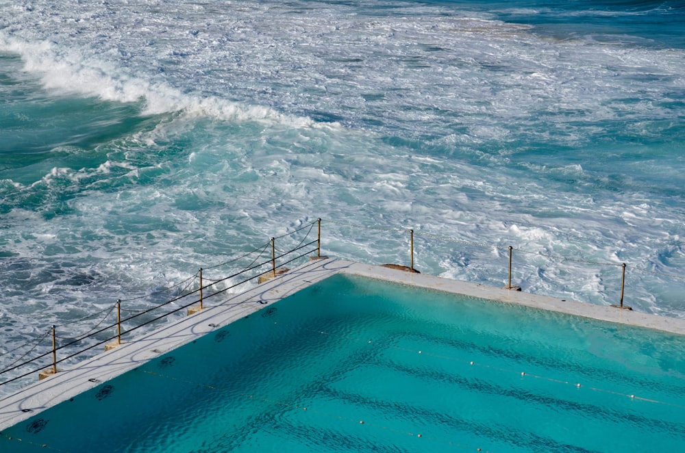 white and brown concrete swimming pool near body of water during daytime