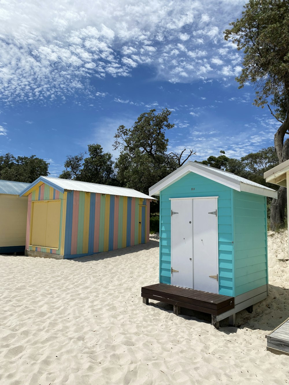 blue green and yellow wooden houses on white sand during daytime