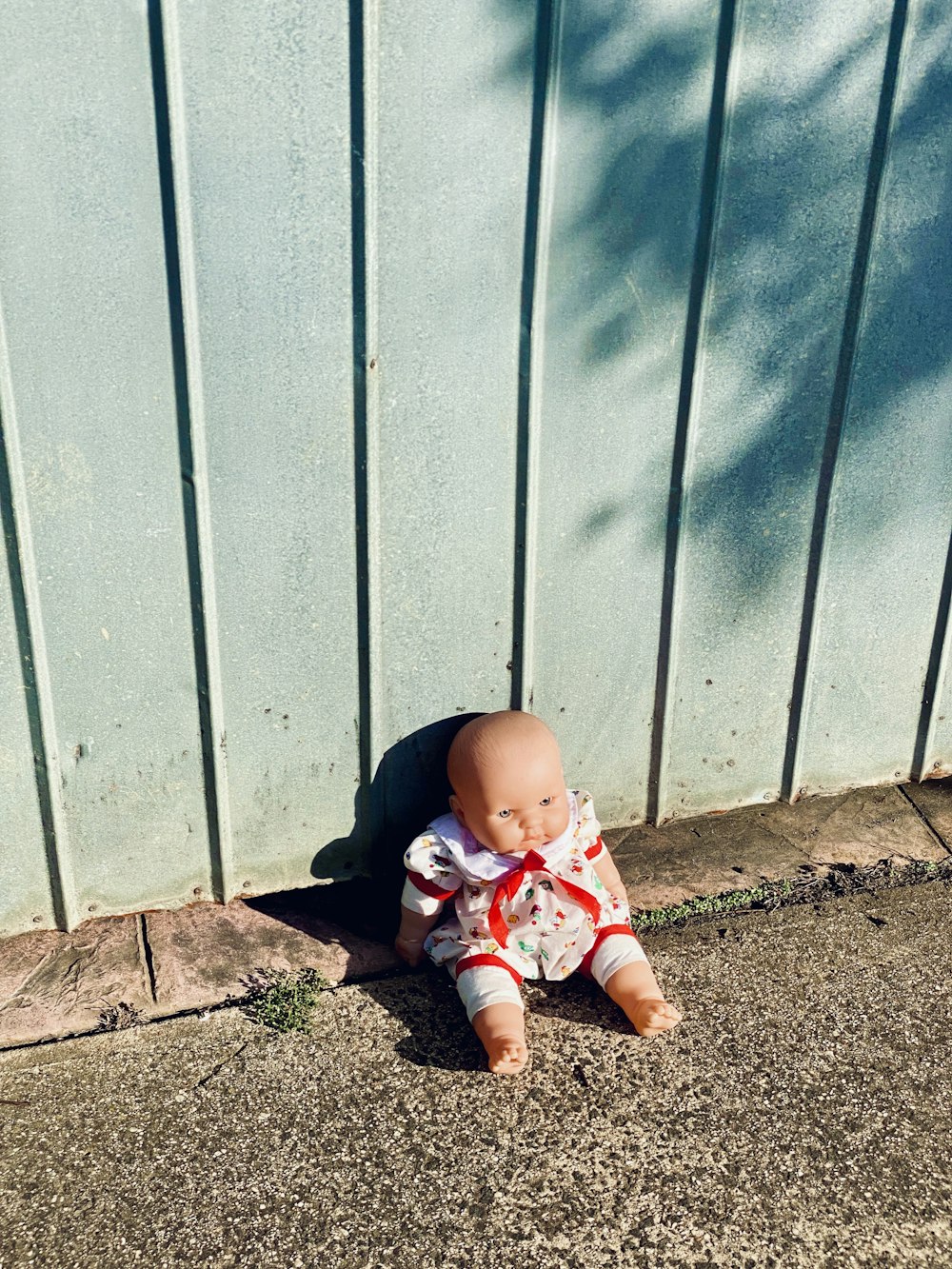 baby in white and red shirt and pants sitting on brown dirt