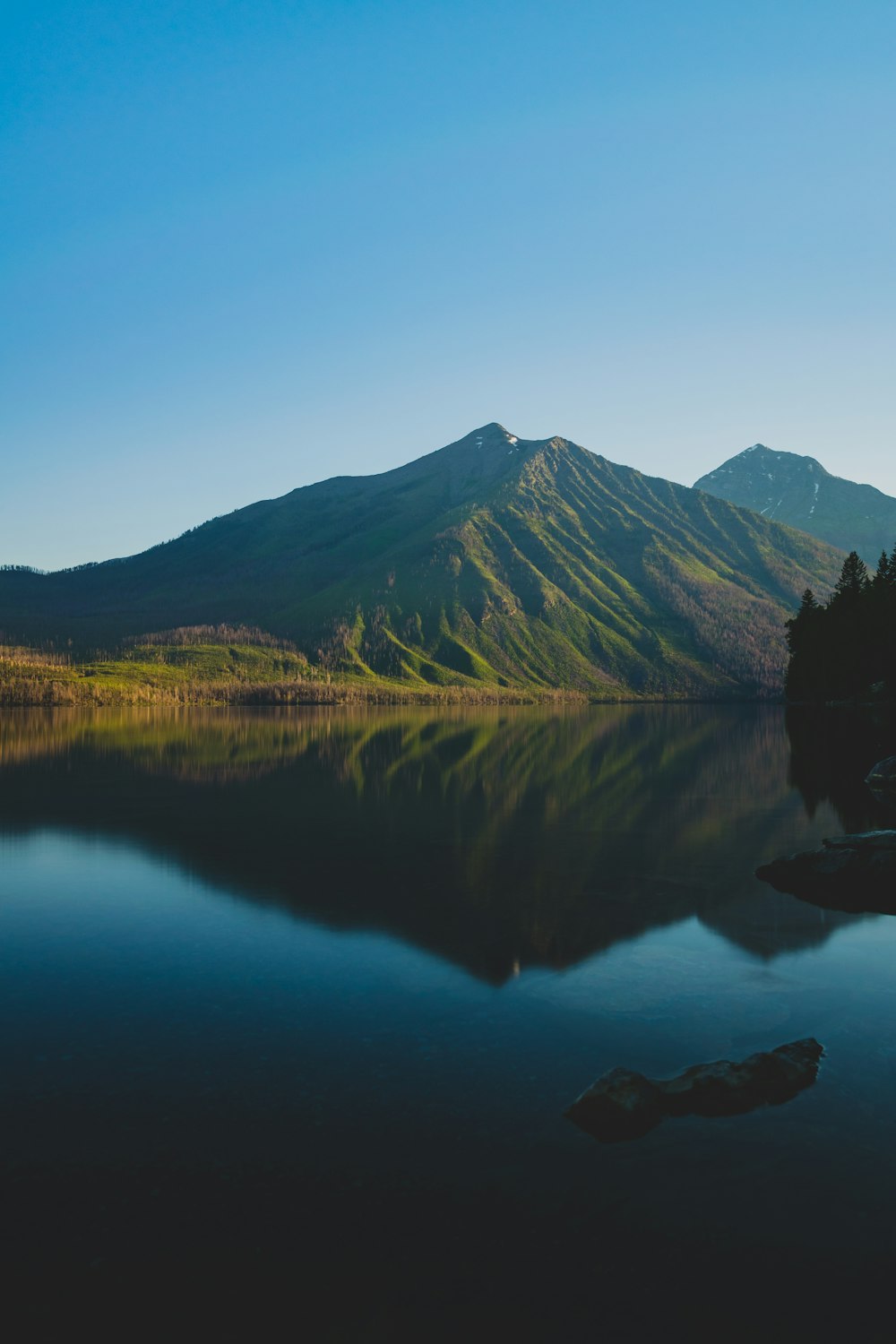 green mountain beside body of water during daytime