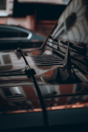 Close-up of a sleek car hood with a glossy ceramic coating reflecting Milwaukee skyline.