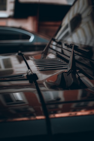 Close-up of a sleek black car hood reflecting the sky after a detailed wash.