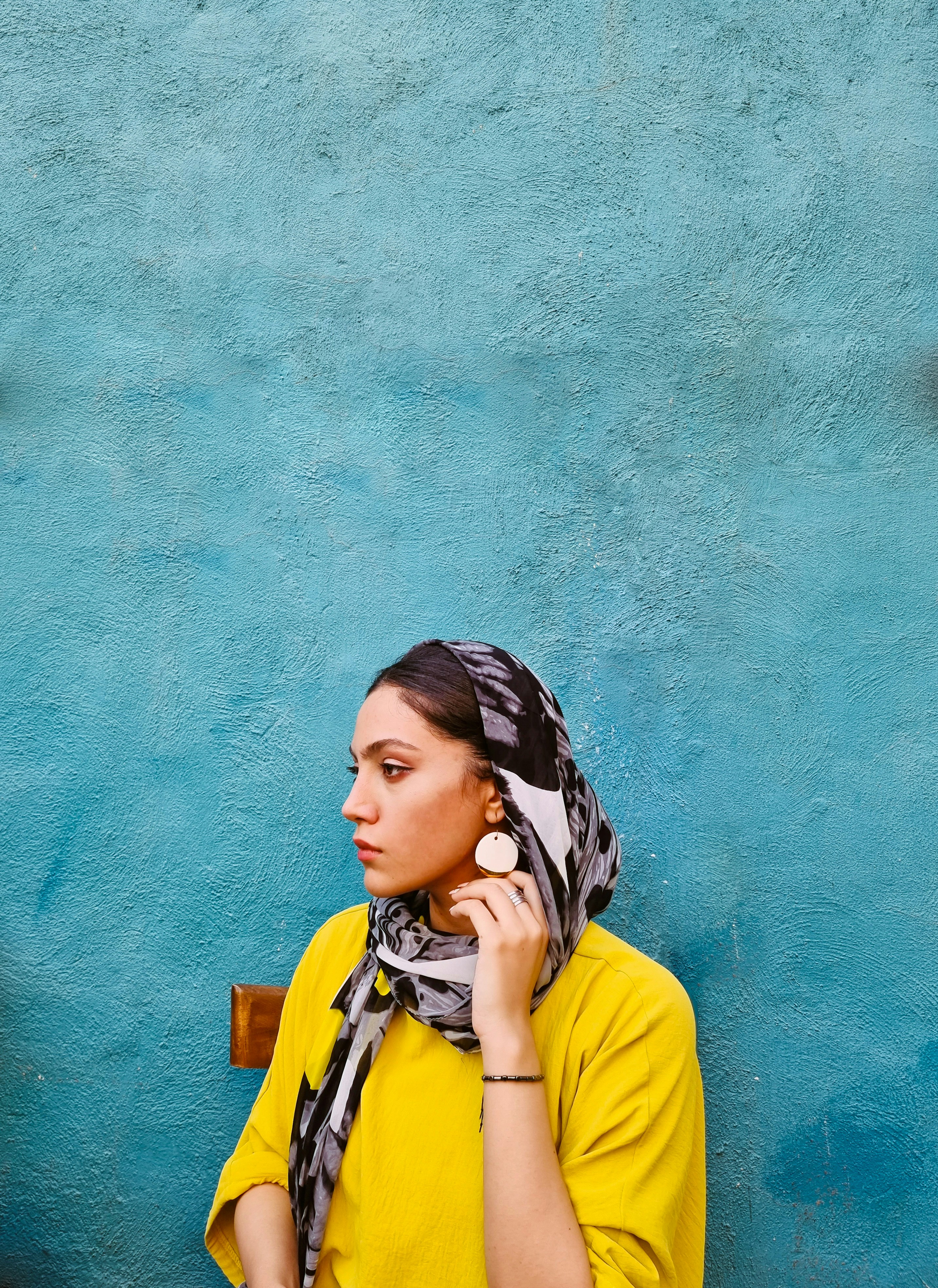 woman in yellow shirt leaning on blue wall