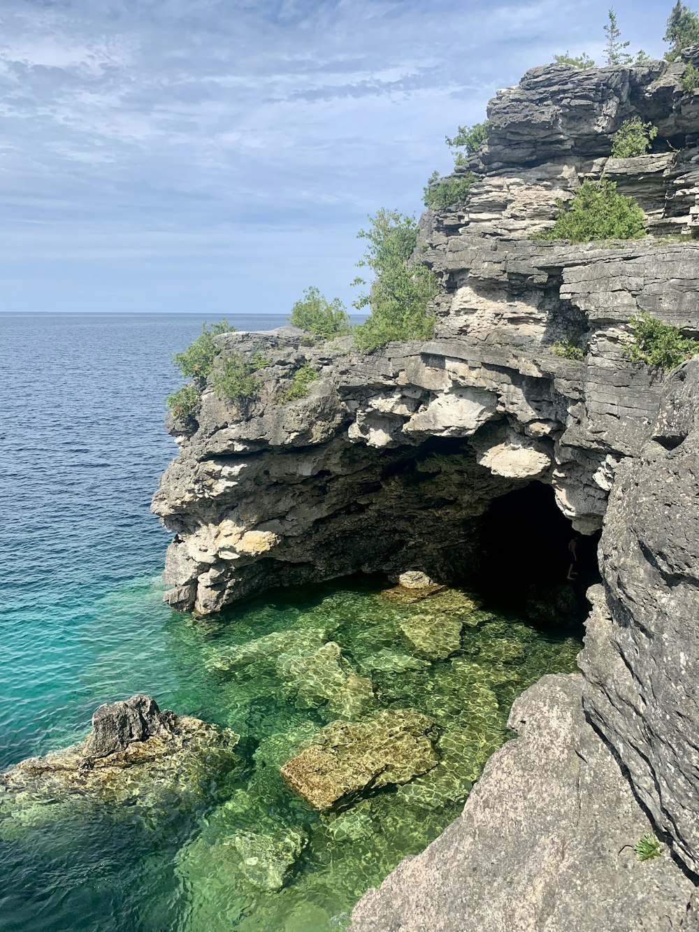 gray rocky cliff near body of water during daytime