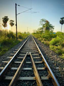 Wide shot of a railway track stretching through lush southern Indian landscape.