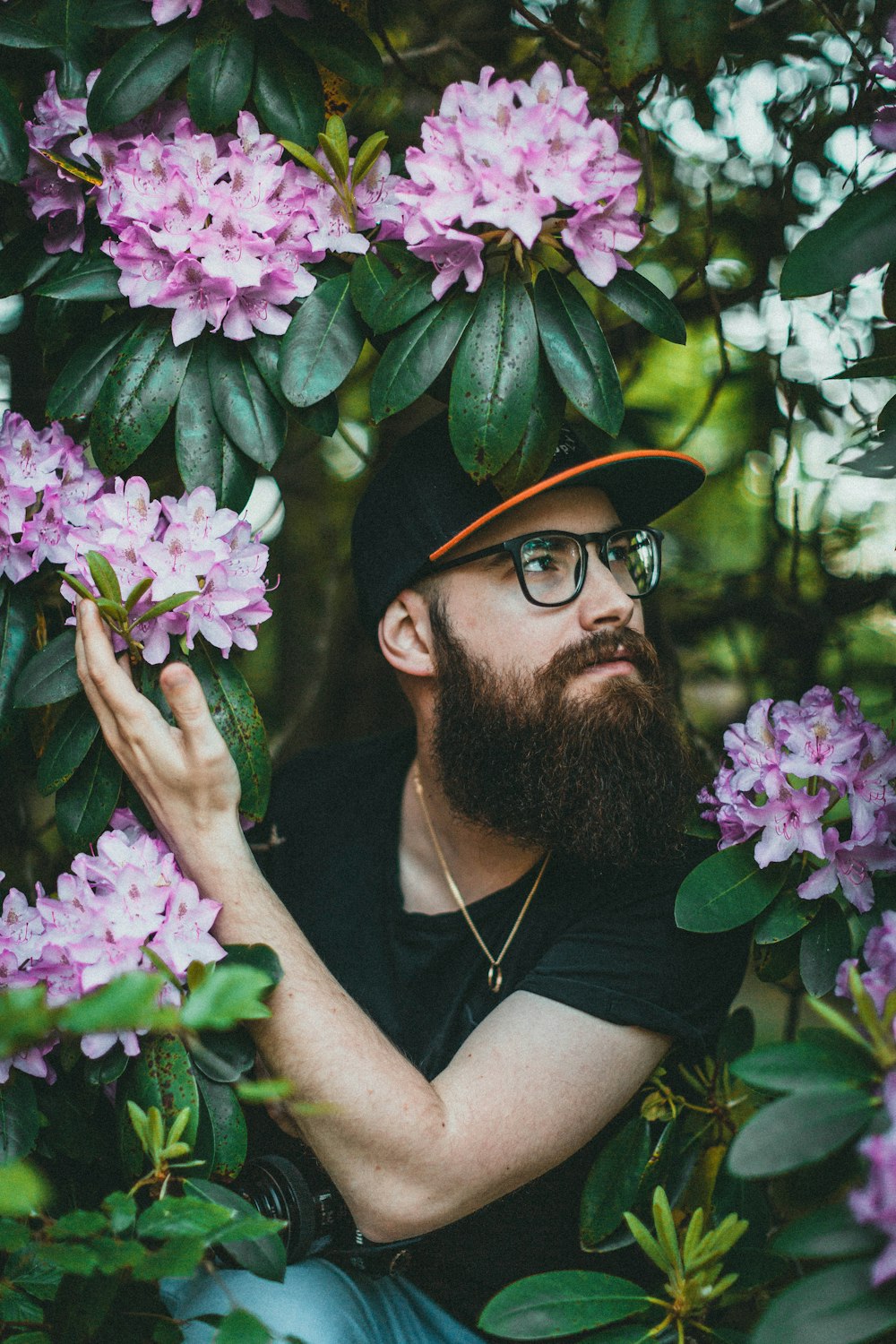 man in black tank top wearing black hat holding purple flowers