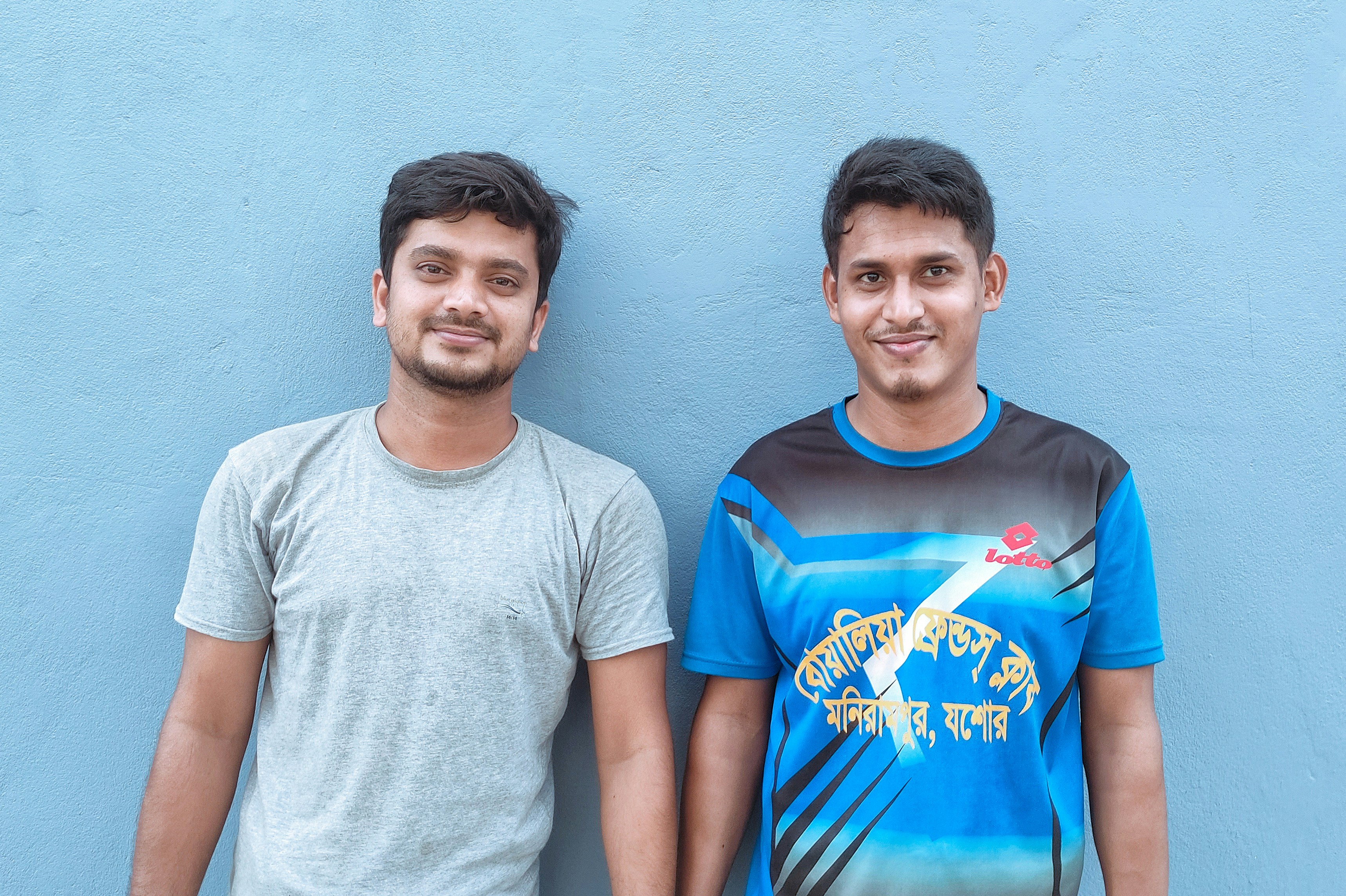 Two men standing beside a white wall
