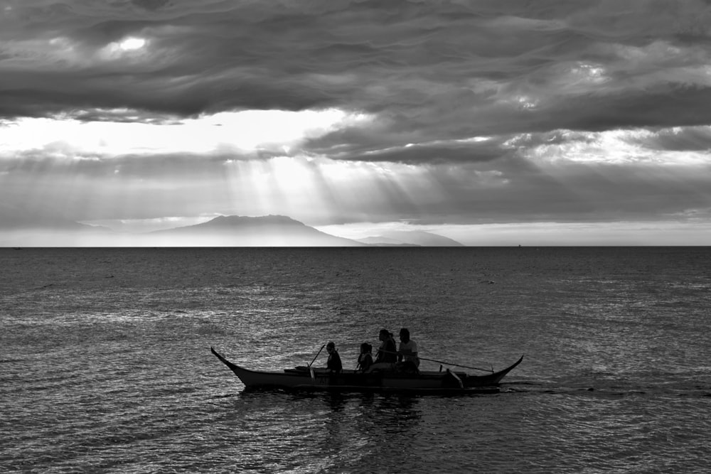 Silhouette von Menschen, die auf einem Boot auf einem Gewässer fahren