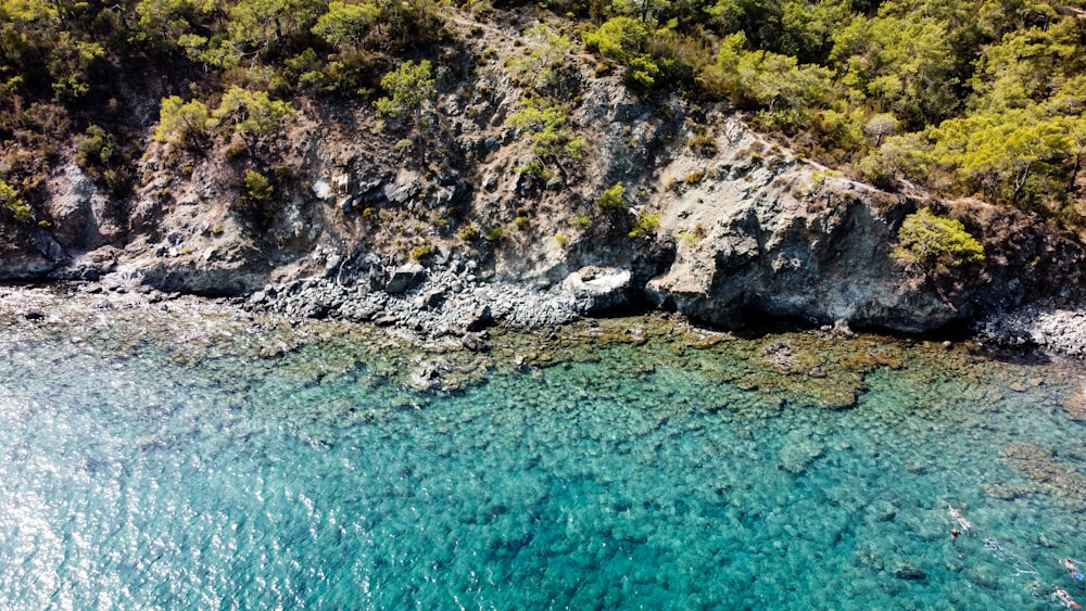 green and brown rocky mountain beside body of water during daytime