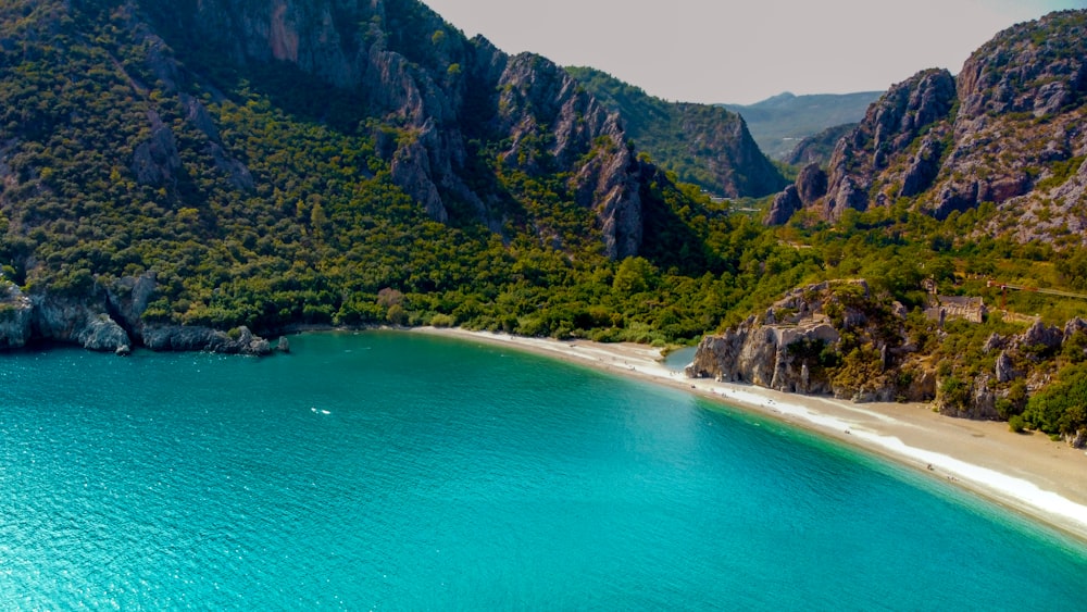 green and brown mountain beside blue sea during daytime