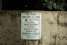 A worn concrete wall displays a sign listing park regulations, including operation hours from daylight to dusk and prohibitions against alcohol, skateboarding, littering, rollerblading, camping, and disorderly conduct. The sign emphasizes that violators will face prosecution.