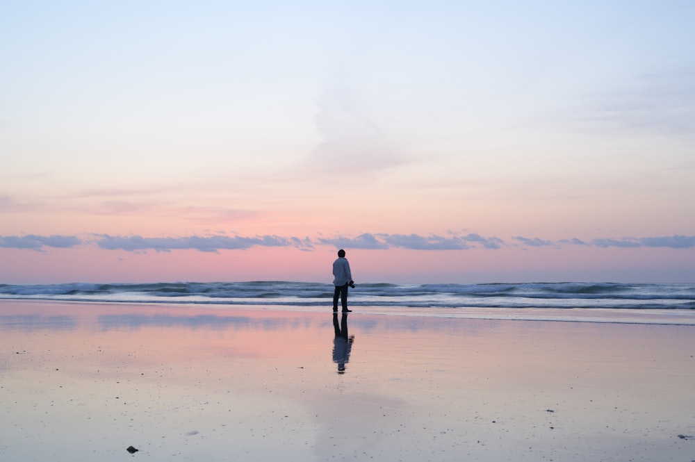 woman in black dress standing on beach during sunset