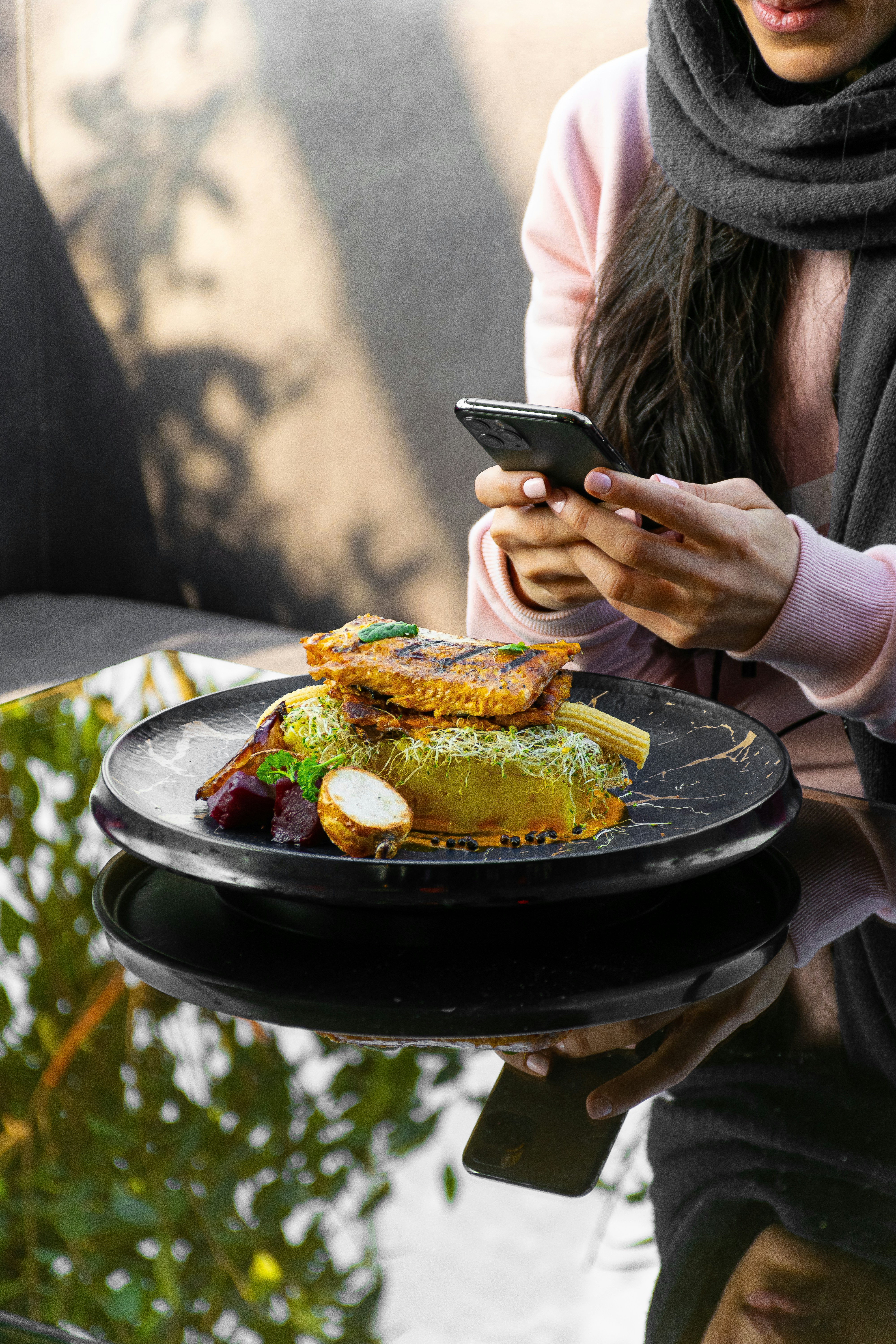 Frau hält schwarzes Smartphone beim Essen