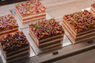 A vintage-style cake stand filled with layered cakes decorated with fresh pistachios and cream.