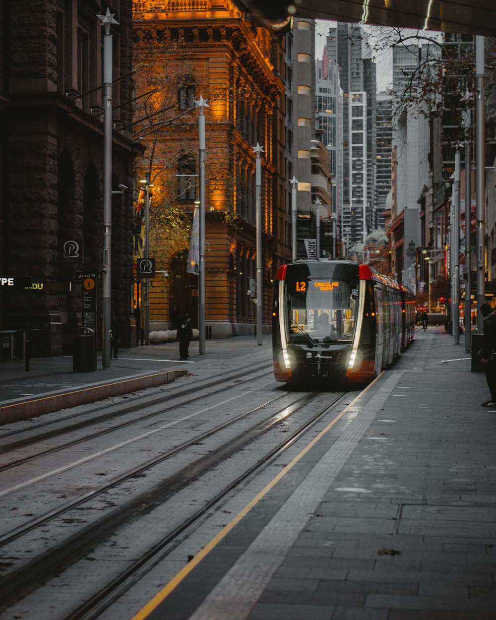 Tramway rouge et noir sur la route entre les immeubles de grande hauteur pendant la journée