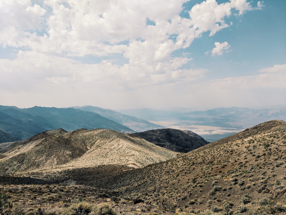 brown and green mountains under white clouds and blue sky during daytime