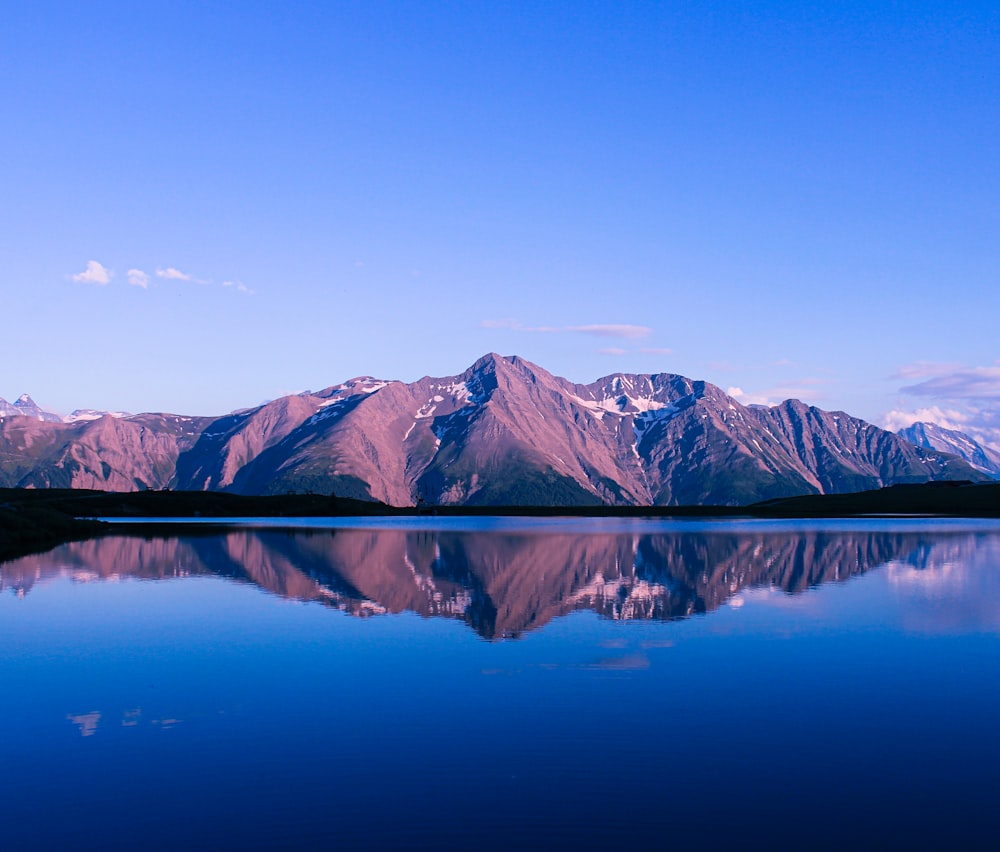 lago azul perto da montanha marrom sob o céu azul durante o dia