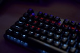 Close-up of a Havit mechanical keyboard glowing with red backlight on a charcoal desk.