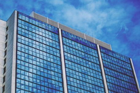 blue and white glass walled building under blue sky