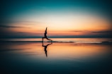 silhouette of person standing on seashore during sunset