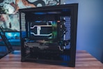 A custom-built desktop computer with a visible internal setup. The components include a Ryzen Threadripper CPU cooler with LED lighting, an XFX Radeon graphics card, and well-organized cables inside a black case. The background features a colorful and artistic mural or wallpaper.