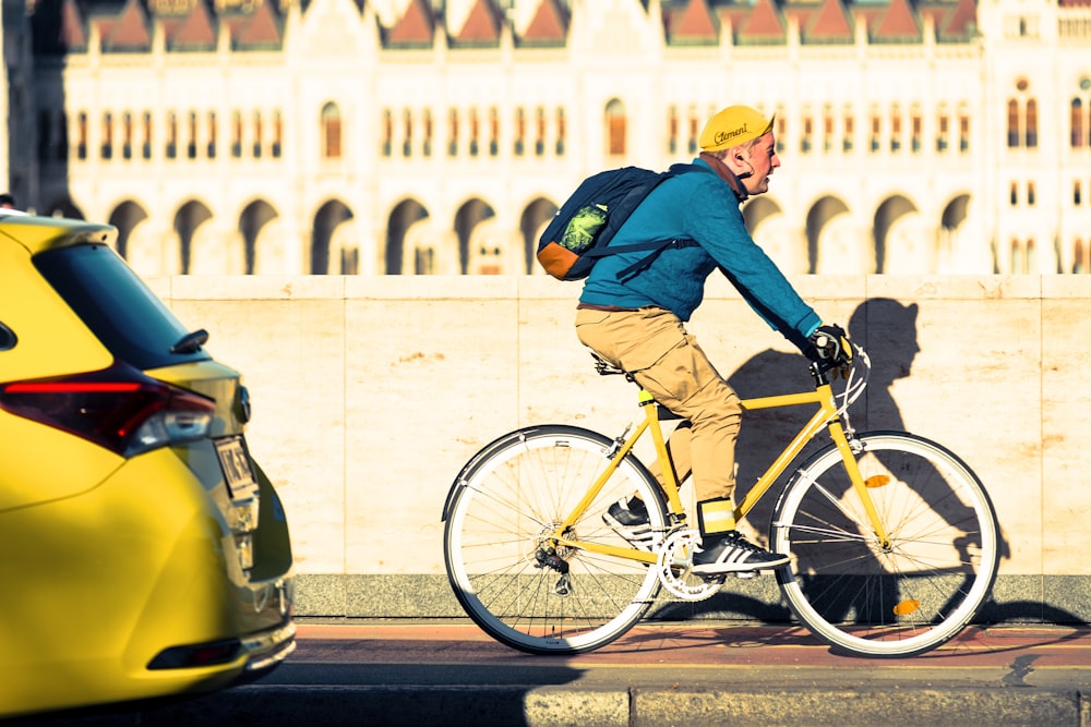 man in blue jacket and black pants riding yellow bicycle