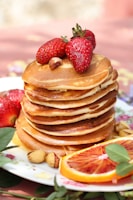 a stack of pancakes topped with fruit and nuts