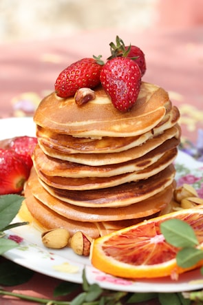 a stack of pancakes topped with fruit and nuts