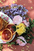 a plate of pancakes, orange slices, and flowers